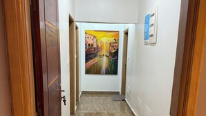 Un pasillo con suelo de baldosas y un cuadro en la pared.