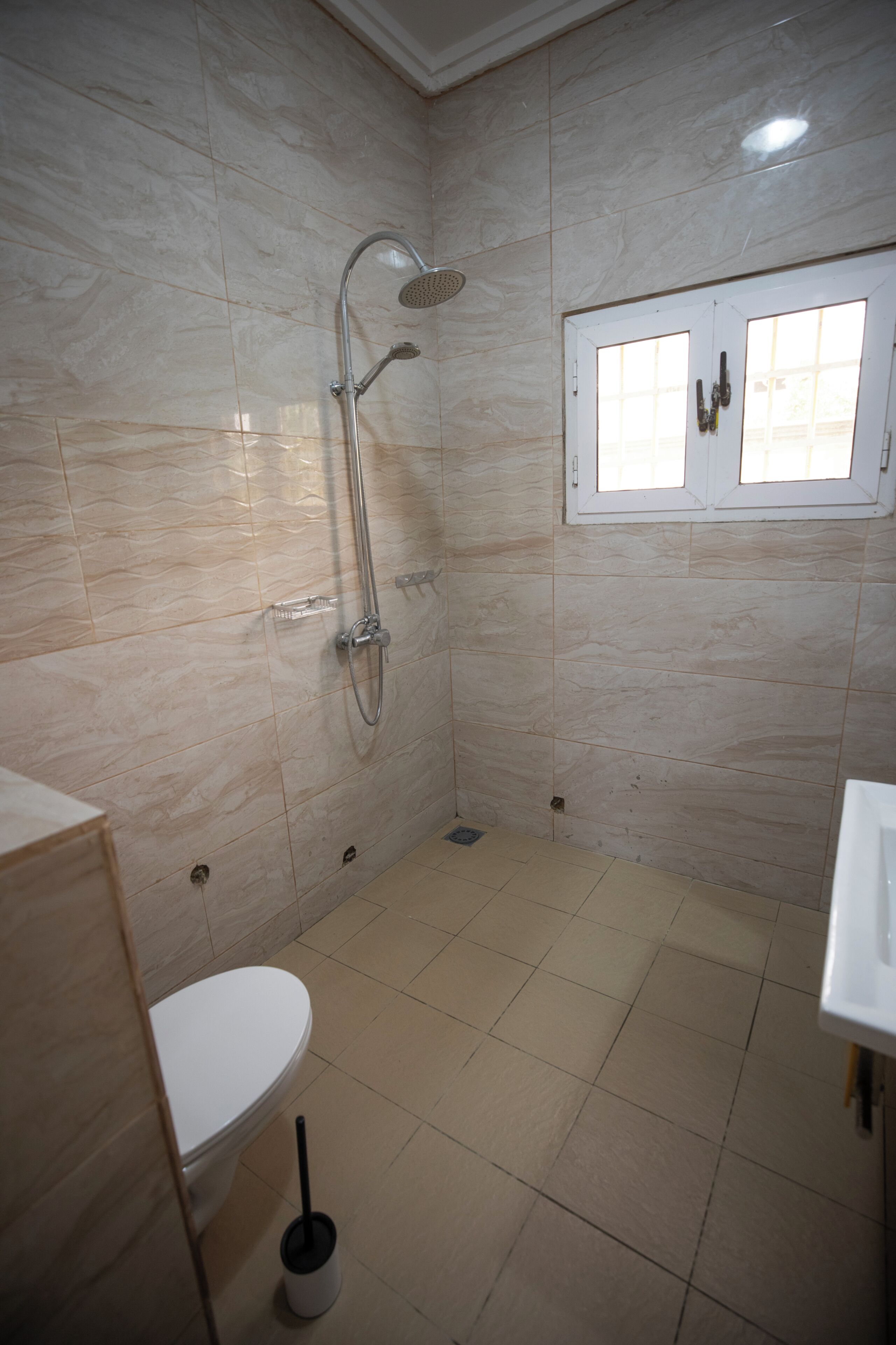 A bathroom with a toilet, a shower, and a window.