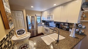 A modern kitchen with granite countertops, stainless steel appliances, and white cabinetry. - Ocean Village Club I35: Pool & Ocean Views 2 Bedroom Condo (St. Augustine)