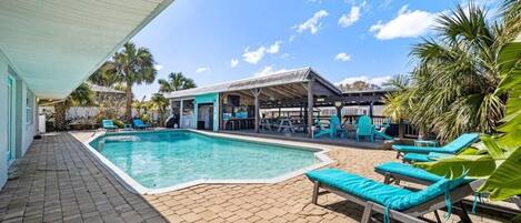 A swimming pool with lounge chairs and a covered seating area.