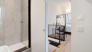 Een moderne badkamer met een douchecabine van glas, een witte badkuip en een houten vloer.
