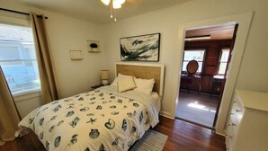 A bedroom with a bed, bedside tables, a ceiling fan, and a view into the adjacent room. - Downtown Getaway - Pet Friendly 3 Bedroom Home (St. Augustine)