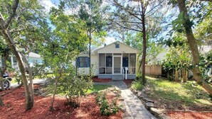 A single-story house with a front porch, surrounded by trees and a pathway. - Downtown Getaway - Pet Friendly 3 Bedroom Home (St. Augustine)