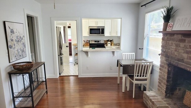 A modern kitchen with white cabinets, a microwave, and a dining area with a table and chairs. - Downtown Getaway - Pet Friendly 3 Bedroom Home (St. Augustine)