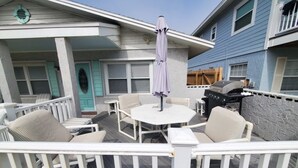 Une terrasse extérieure avec des meubles blancs, une table ronde et un parasol violet.