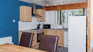 A compact kitchen with wooden cabinets, a microwave, a stove, and a refrigerator.