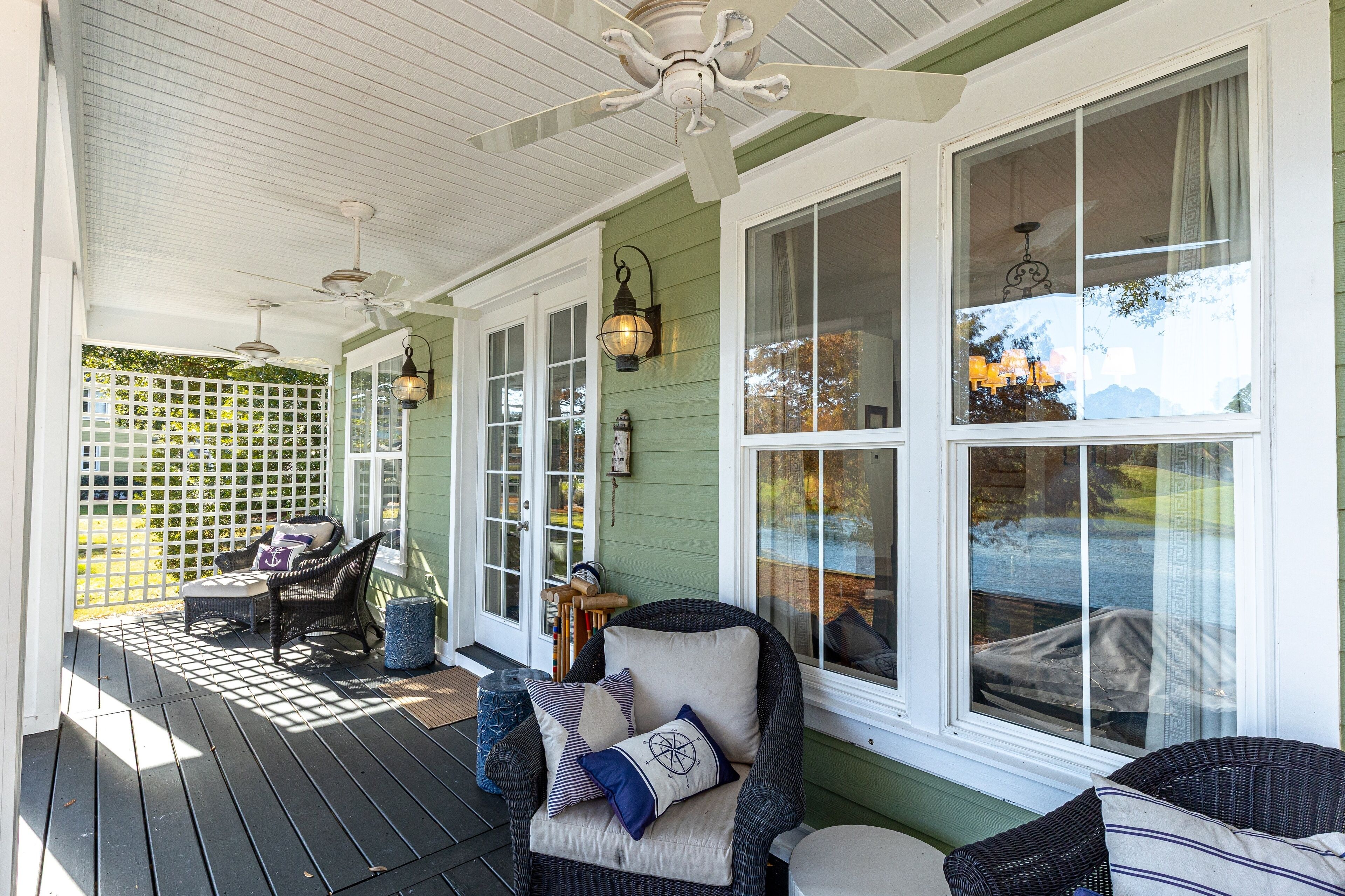 A covered porch with wicker furniture, a ceiling fan, and a view of the outdoors.