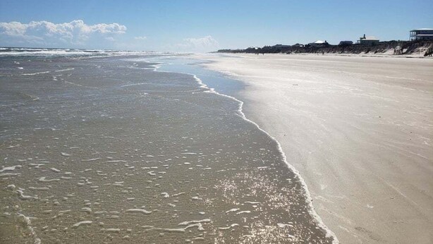 Une plage avec un large rivage sablonneux et un ciel dégagé.