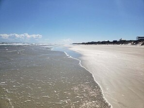 Ein Strand mit weitem Sandufer und blauem Himmel.