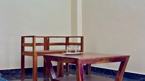 A wooden table and chair set in a corner with a marble floor and a plain wall. - Sunset luxury Private Farmhouse (Gurgaon)