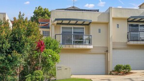 A residential building with a garage, a balcony, and a well-maintained garden. - Flynns Beach Retreat, 3 of 3 Everard street (Port Macquarie)