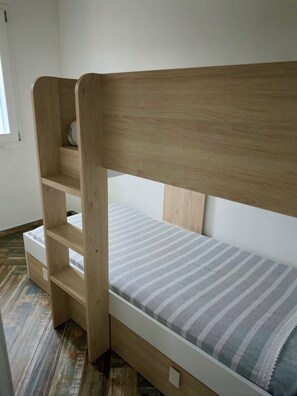 A wooden bunk bed with a striped mattress, a shelf, and a small storage drawer. - Castelsardo Apartment - Between Blue and Heavenly A beautiful view of the sea (Castelsardo)