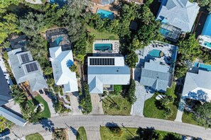 An aerial view of a residential area with multiple houses, solar panels, swimming pools, and a well-maintained lawn. - Fully renovated 5 bedroom pool home (Sarasota)
