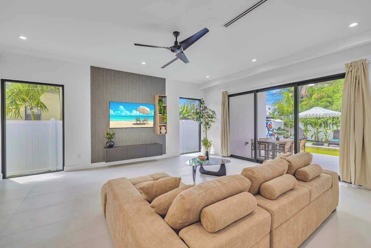 Uma sala de estar moderna com um sofá grande, uma televisão de tela plana e um ventilador de teto.