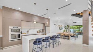 Una cocina moderna con una isla central, taburetes de bar e iluminación colgante.