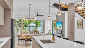 Una cocina moderna con una isla central, zona de comedor y televisor.