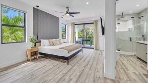 Une chambre moderne avec un grand lit, un ventilateur de plafond et une vue sur l’extérieur.