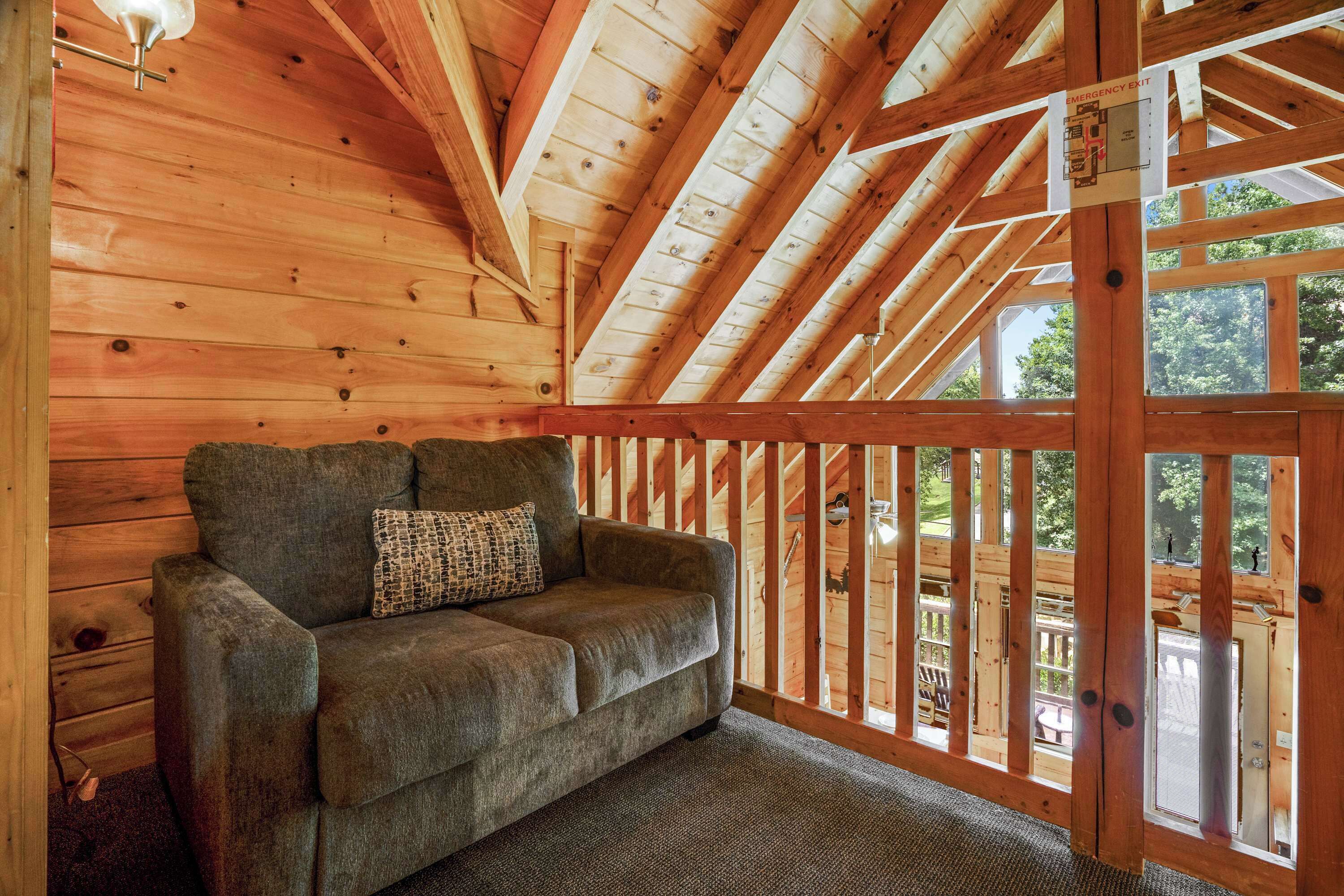 Interior de madera con sofá y vistas al exterior desde un balcón.