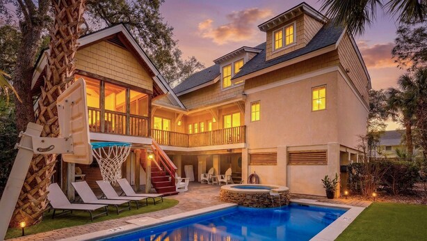 A two-story house with a swimming pool, outdoor seating, and a basketball hoop. - 50 Dune Lane – NFB Oceanside Retreat- Private Pool, Steps from the Beach (Hilton Head Island)