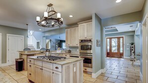 A kitchen with a central island, built-in oven, and a chandelier. - 50 Dune Lane – NFB Oceanside Retreat- Private Pool, Steps from the Beach (Hilton Head Island)