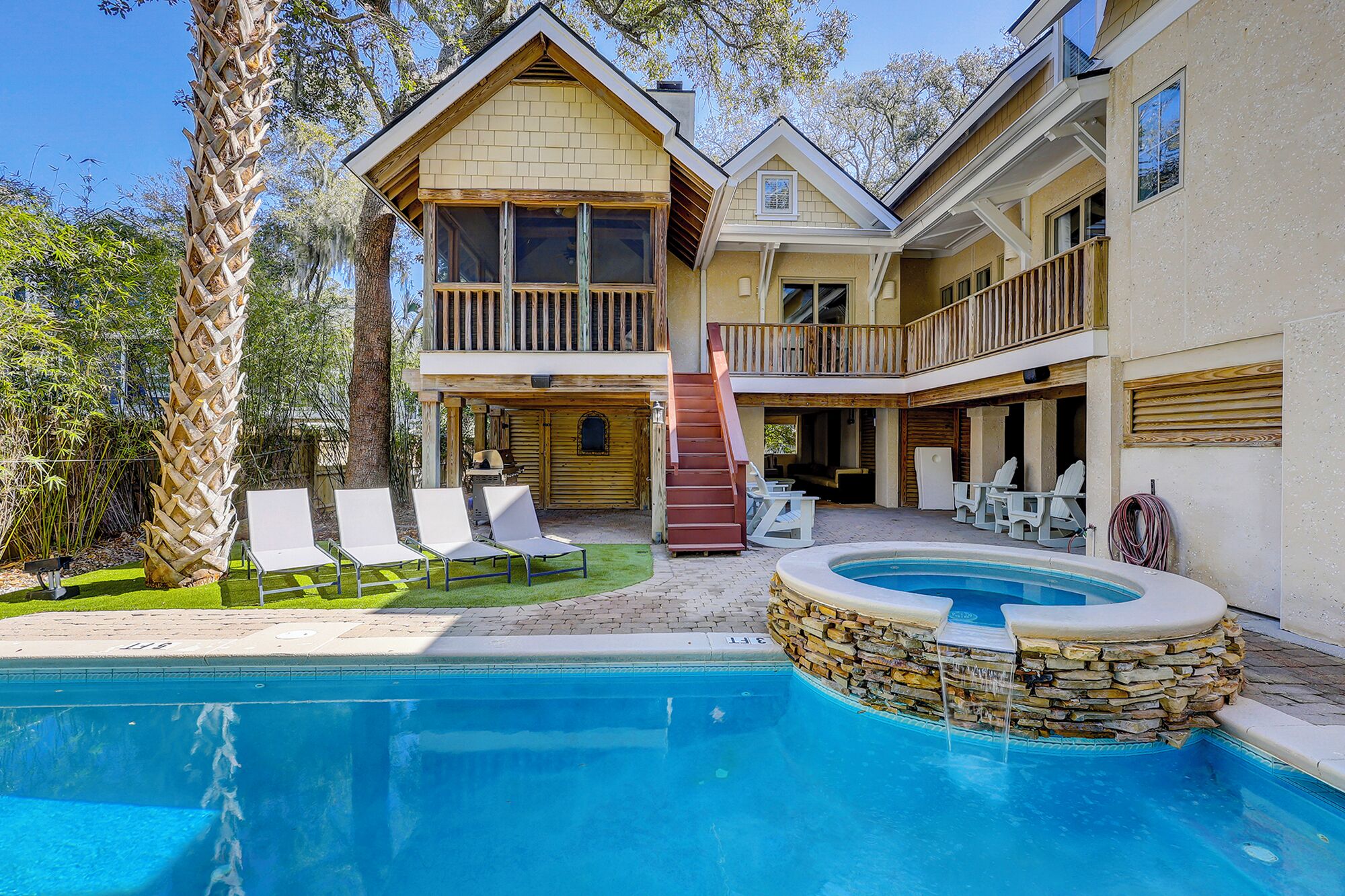 Une maison à deux étages avec une piscine, un espace salon extérieur et une terrasse couverte.
