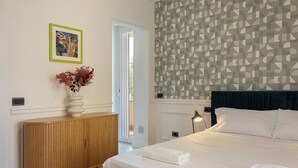 Ein Schlafzimmer mit einem Bett, einem Holzschrank, einer Vase mit Trockenblumen und einer Wand mit geometrischem Muster.