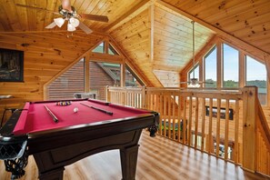 A pool table in a room with wooden walls and a sloped ceiling, large windows, and a view of the outdoors. - Handicap Friendly Cabin Retreat・Pool Table・Grill (Pigeon Forge)