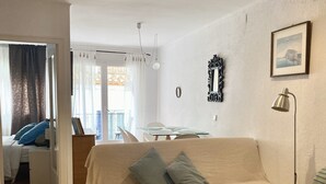 Una sala de estar con un sofá, una mesa de centro y un comedor con una mesa y sillas.