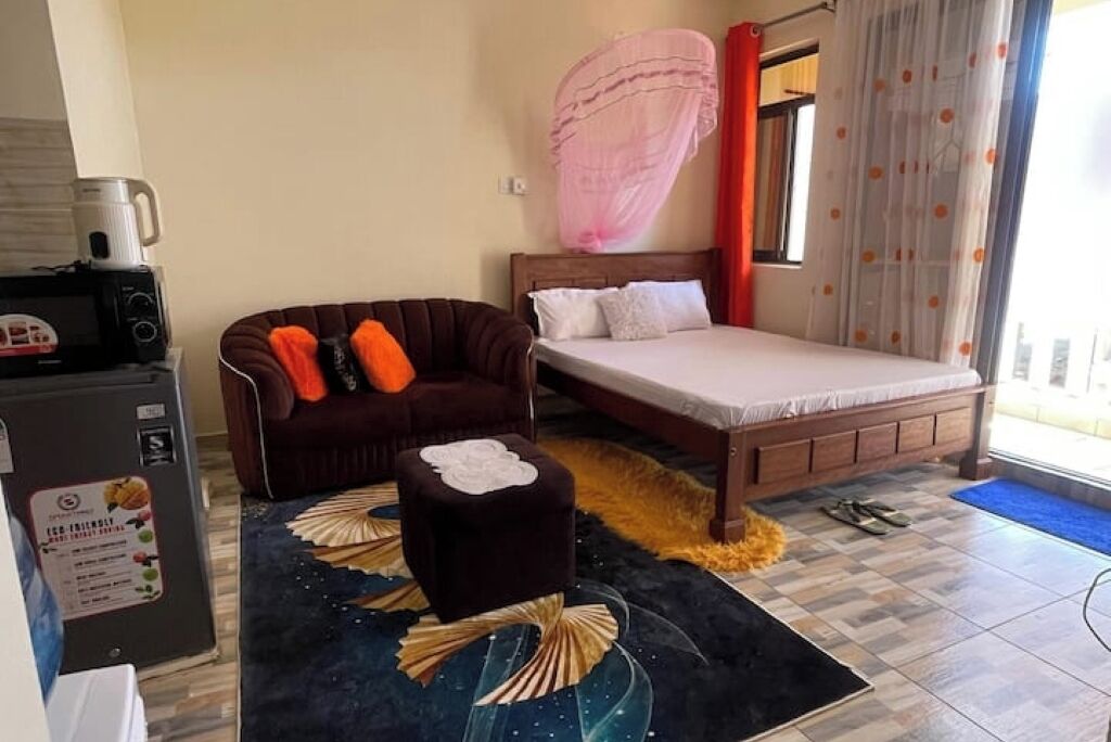 Une chambre à coucher comprenant un lit, un canapé, une petite table et un réfrigérateur.