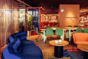 A modern interior with seating arrangements, a coffee table, and a potted plant. - Scandic Go, Lilla Bommen 5 (Gothenburg)