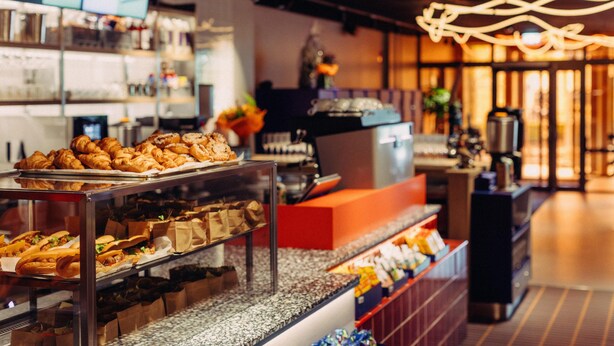 Eine Verkaufstheke mit Gebäck, Sandwiches, einer Kaffeemaschine und einer Speisekarte.