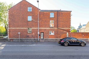 A red brick building with multiple windows and a black car parked in front. - 1Bed · Cardiff Centre · Sleeps 2 (Cardiff)