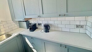 Une cuisine avec des meubles de couleur bleu clair, un plan de travail blanc et un pare-feu en carreaux.