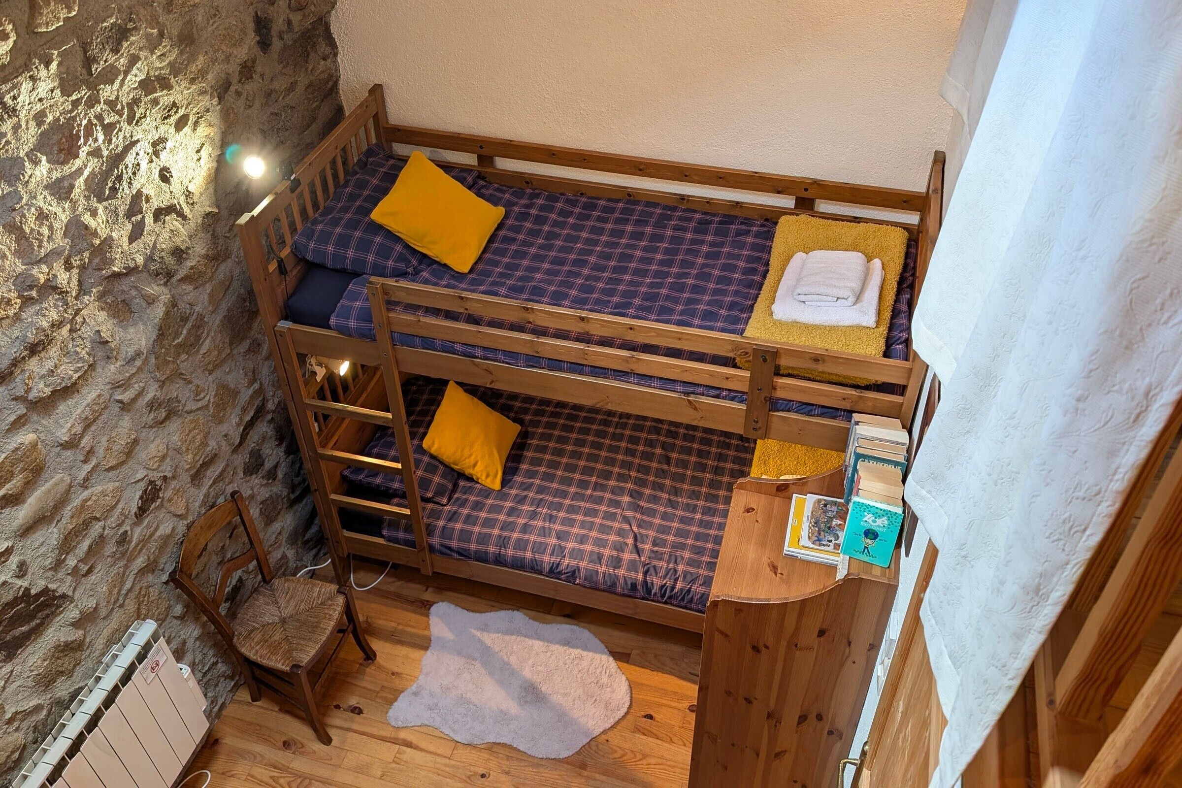 Un lit superposé avec un matelas à carreaux, un oreiller jaune et une serviette blanche.