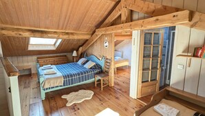 Een houten kamer met een bed, een stoel, een tafeltje en een raam.