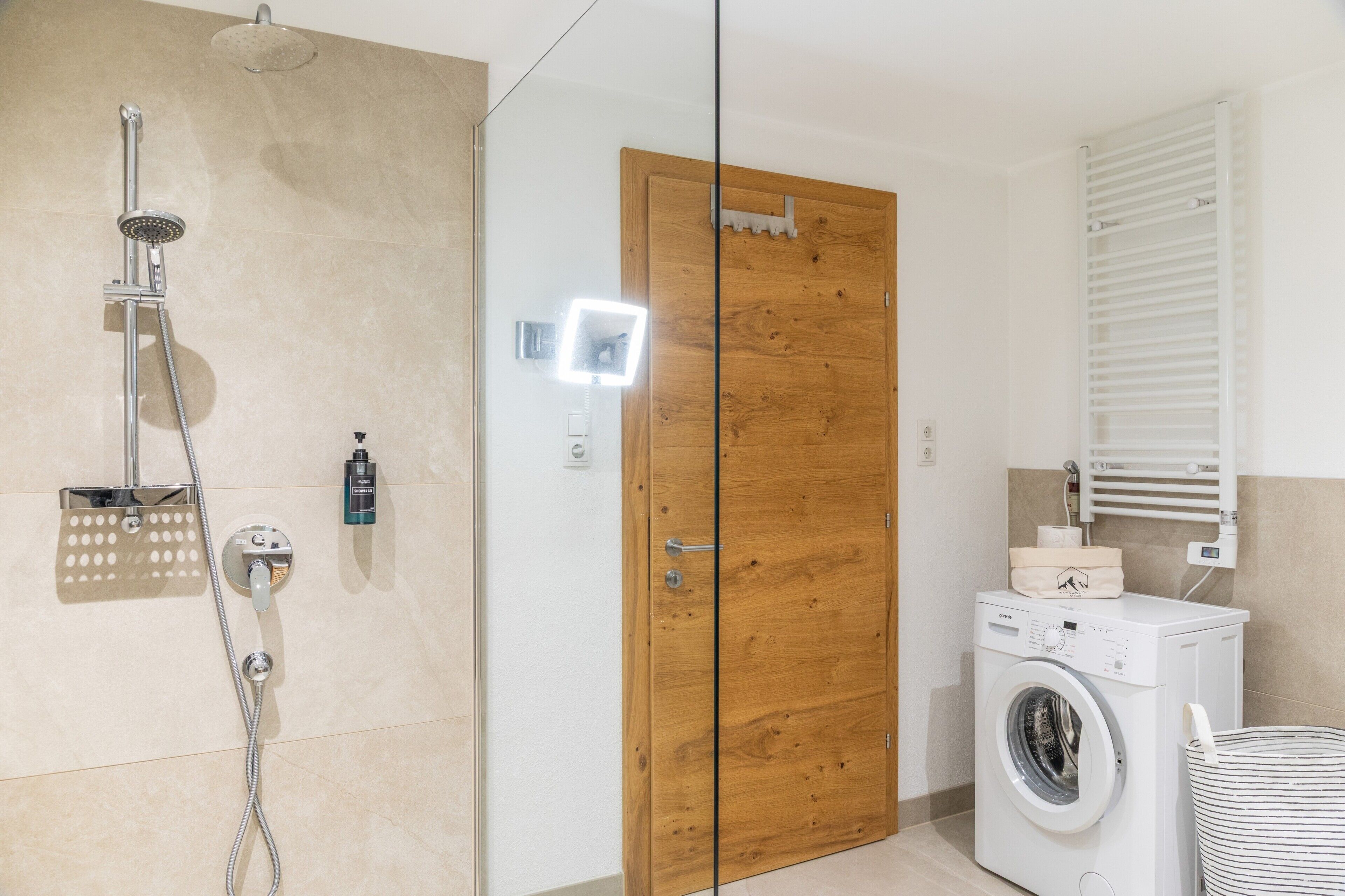 Ein Badezimmer mit Dusche, einer Holztür, einer Waschmaschine und einem Handtuchhalter.