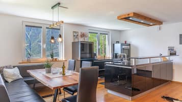 A modern kitchen with a central island, wooden flooring, and large windows.