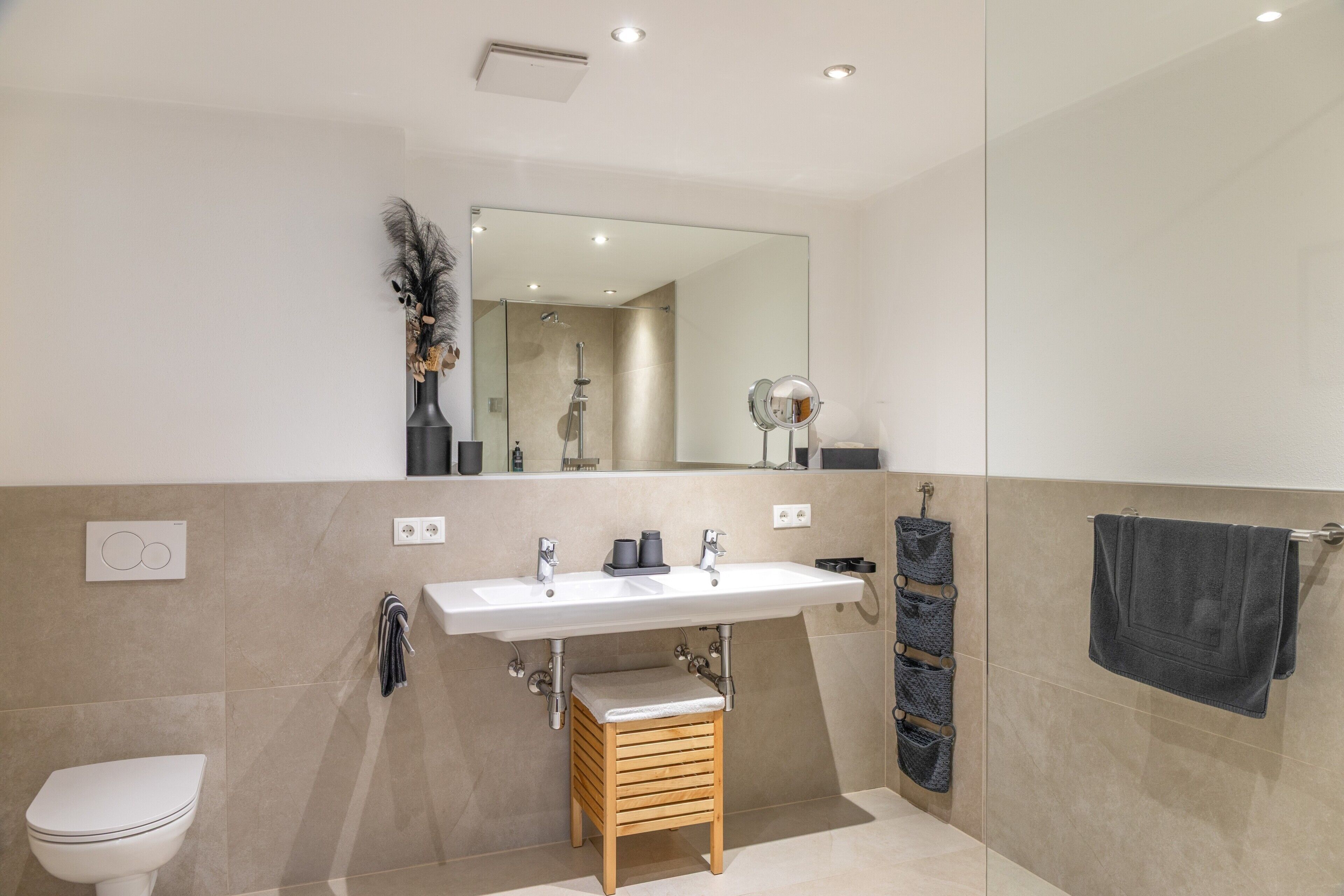 Ein modernes Badezimmer mit einem großen Spiegel, einem Waschbecken, einer Toilette und einer Dusche.