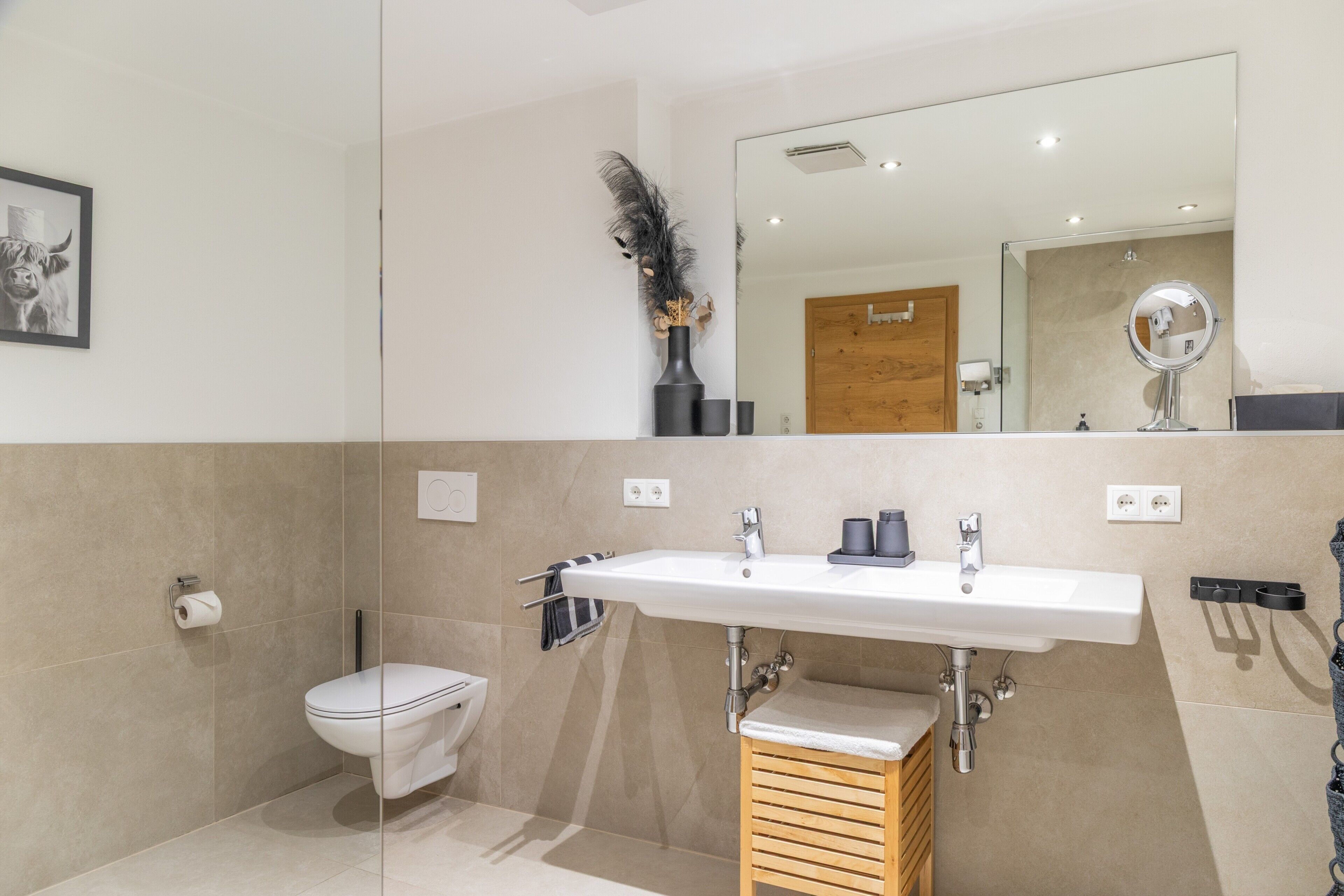 Een moderne badkamer met toilet, wastafel en spiegel.