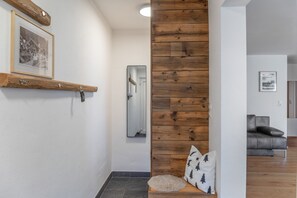 A hallway with a wooden accent wall, a mirror, a framed picture, and a sofa in the background.