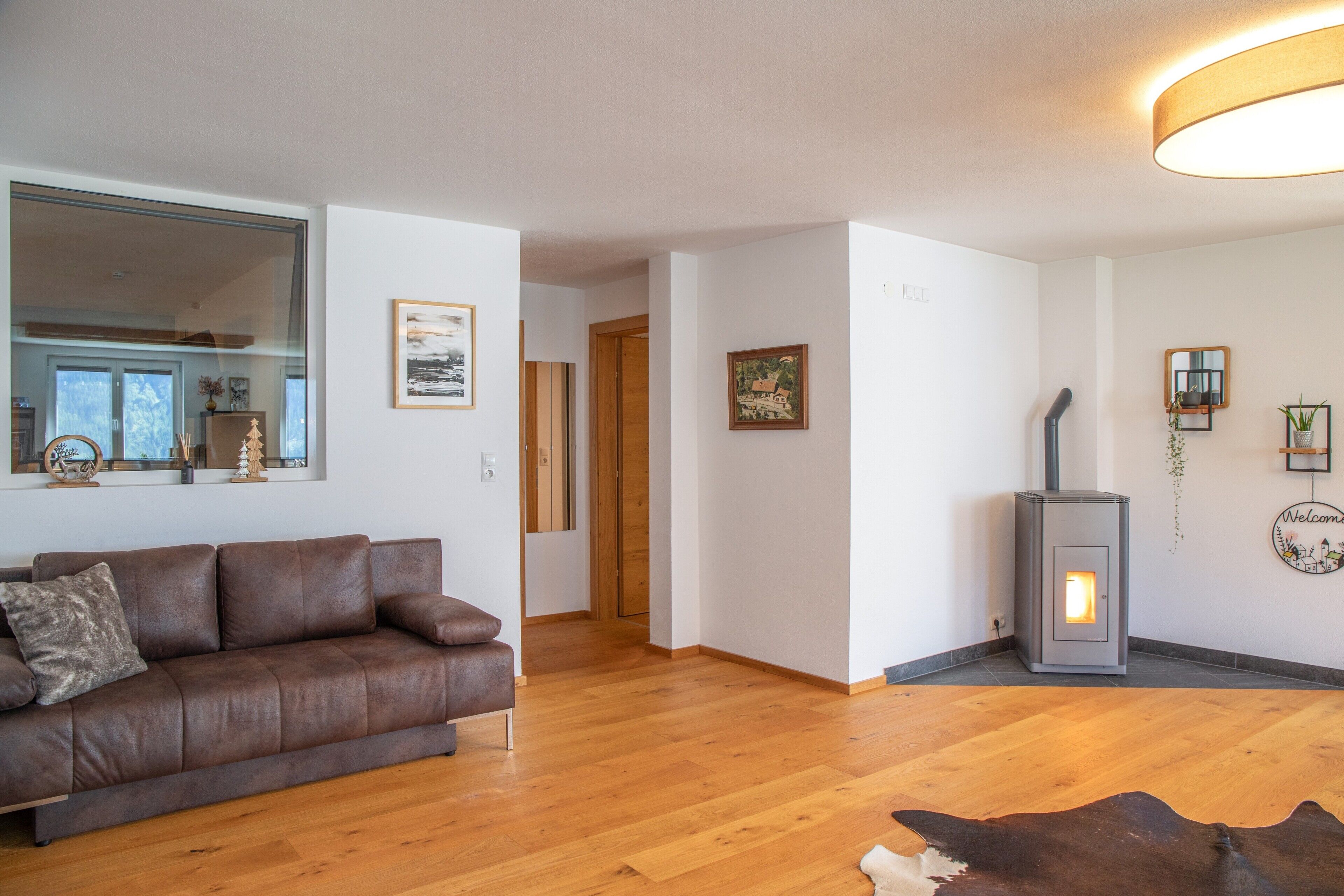 A living room with a brown leather sofa, wooden flooring, a fireplace, and a mirror on the wall.