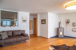 Una sala de estar con un sofá de cuero marrón, piso de madera, una chimenea y un espejo en la pared.
