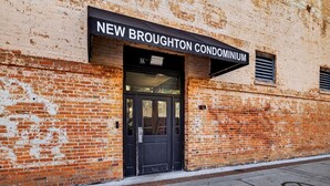 Ein Gebäude mit einem Schild, auf dem 'NEW BROUGHTON CONDOMINIUM' steht.