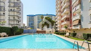 Piscina com águas cristalinas e azuis, rodeada por edifícios de apartamentos.