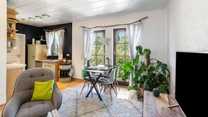 Uma sala moderna com área de refeições, televisão e uma grande janela com cortinas.