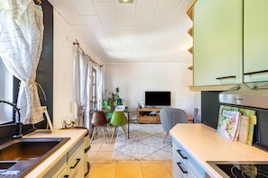 Eine moderne Küche mit Bosch-Dunstabzugshaube, einem Essbereich mit Fernseher und einem Bücherregal.