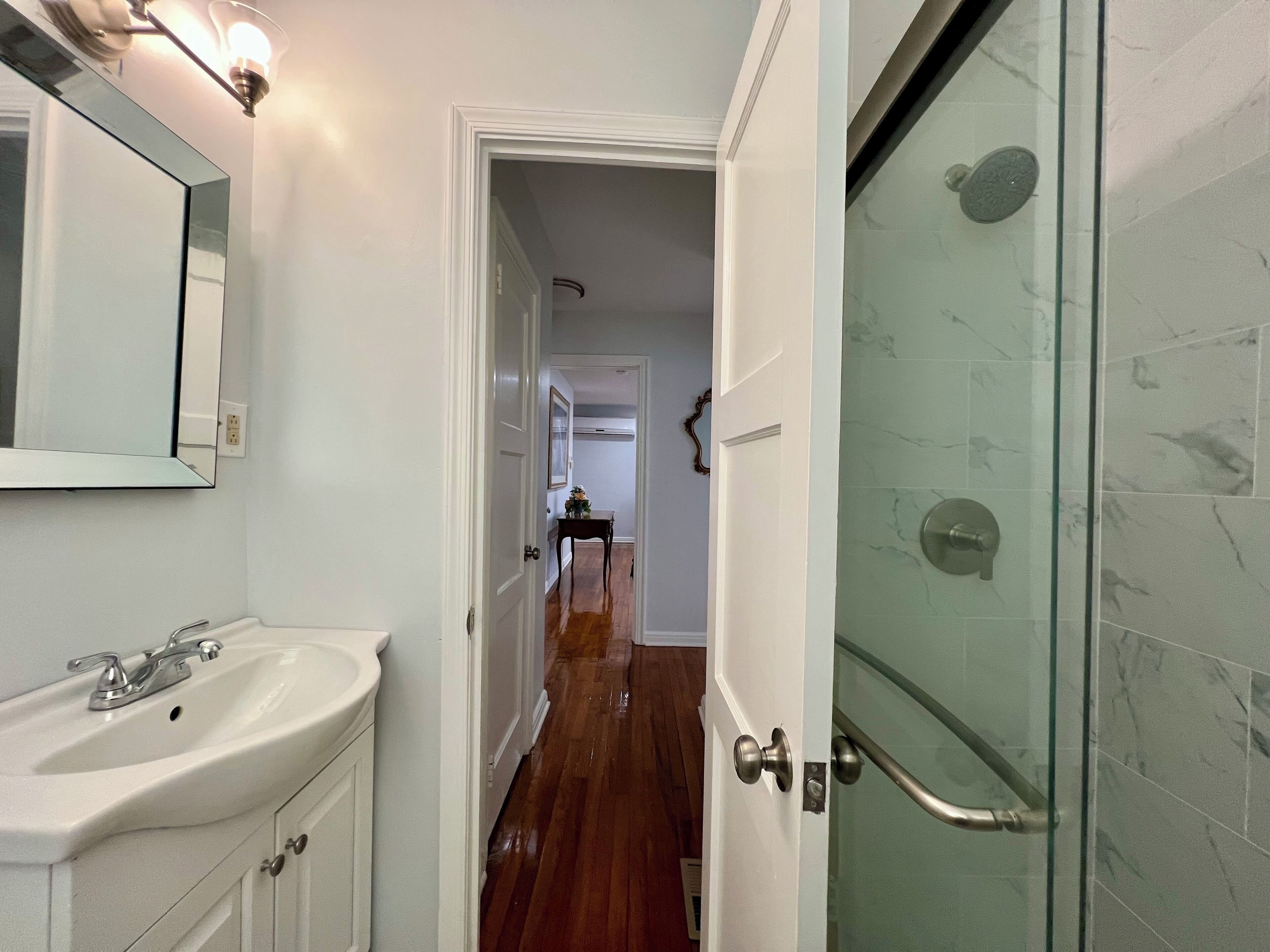 A bathroom with a white sink, a mirror, and a glass shower enclosure.