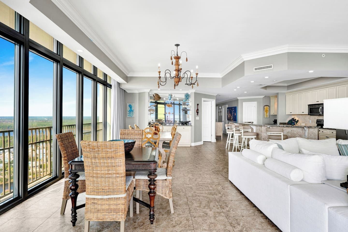 A spacious living area with a dining table, white sofas, and a large window offering a view.