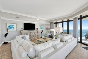 A spacious living room with a large white sofa, a flat-screen TV, and artwork on the walls. - Oasis 2201 | Beachfront 4 BR with Gulf Sunsets from Every Bedroom | Sleeps 10 (Orange Beach)