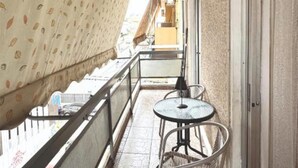 A narrow balcony with patterned curtains, a small round table, and a chair. - An Athenian gem by the Acropolis (Athens)